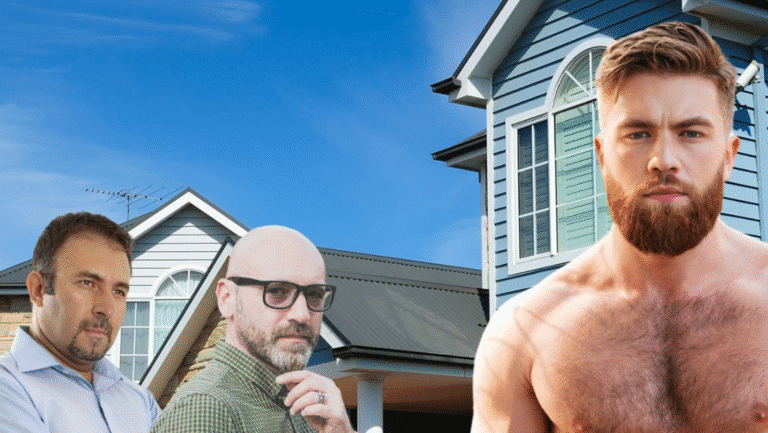 Three men stand in front of modern suburban houses. Two are older and wear glasses and casual shirts, while the third is a younger, muscular man with a beard and bare chest. The sky is clear and blue.