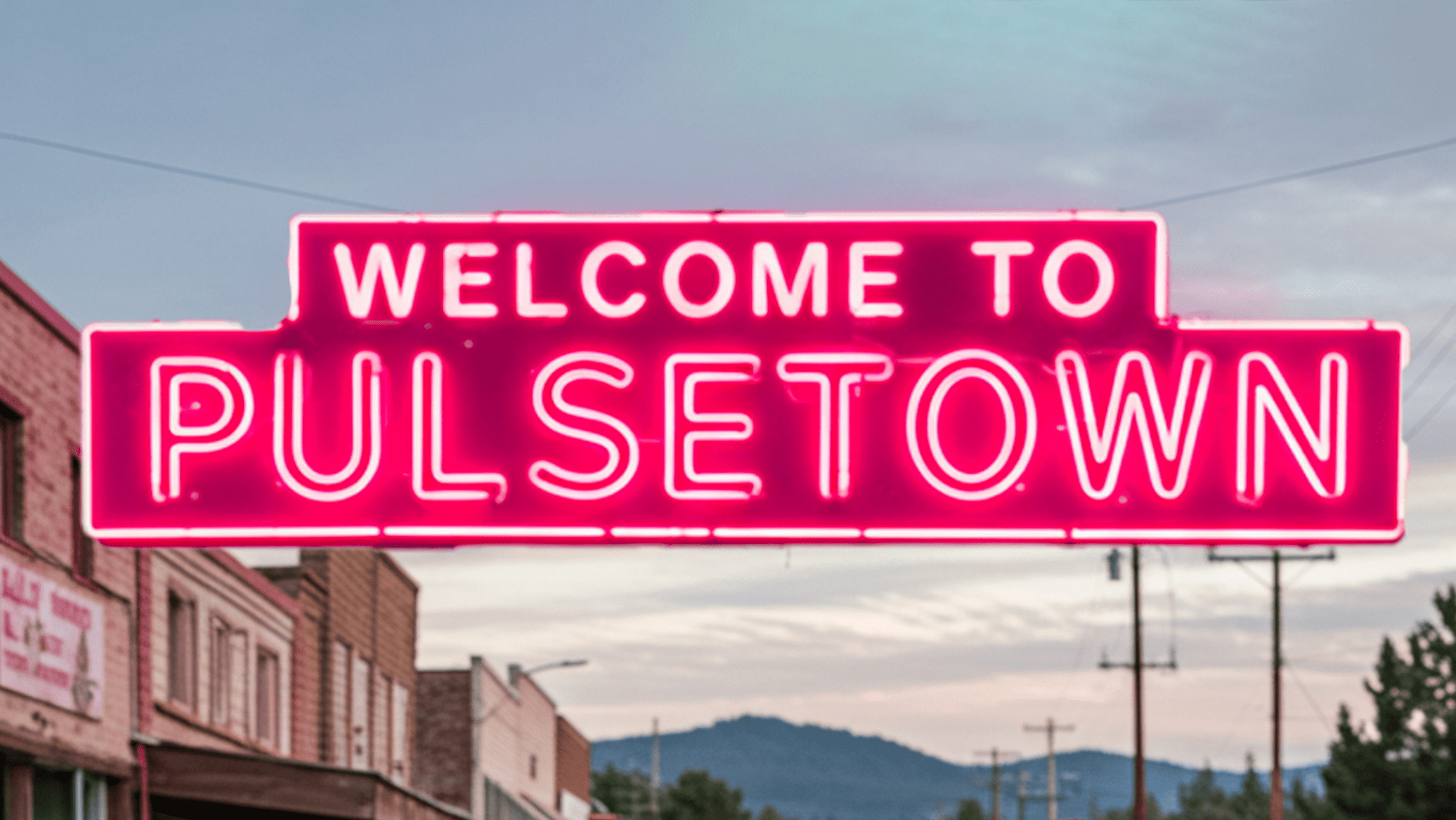 Bright pink neon sign reads WELCOME TO PULSETOWN above a street with buildings and distant mountains visible in the background under a partly cloudy sky.