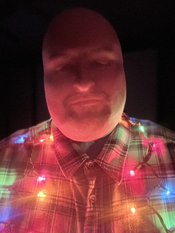Jay Hypno in a stocking mask with festive Christmas lights around His neck.